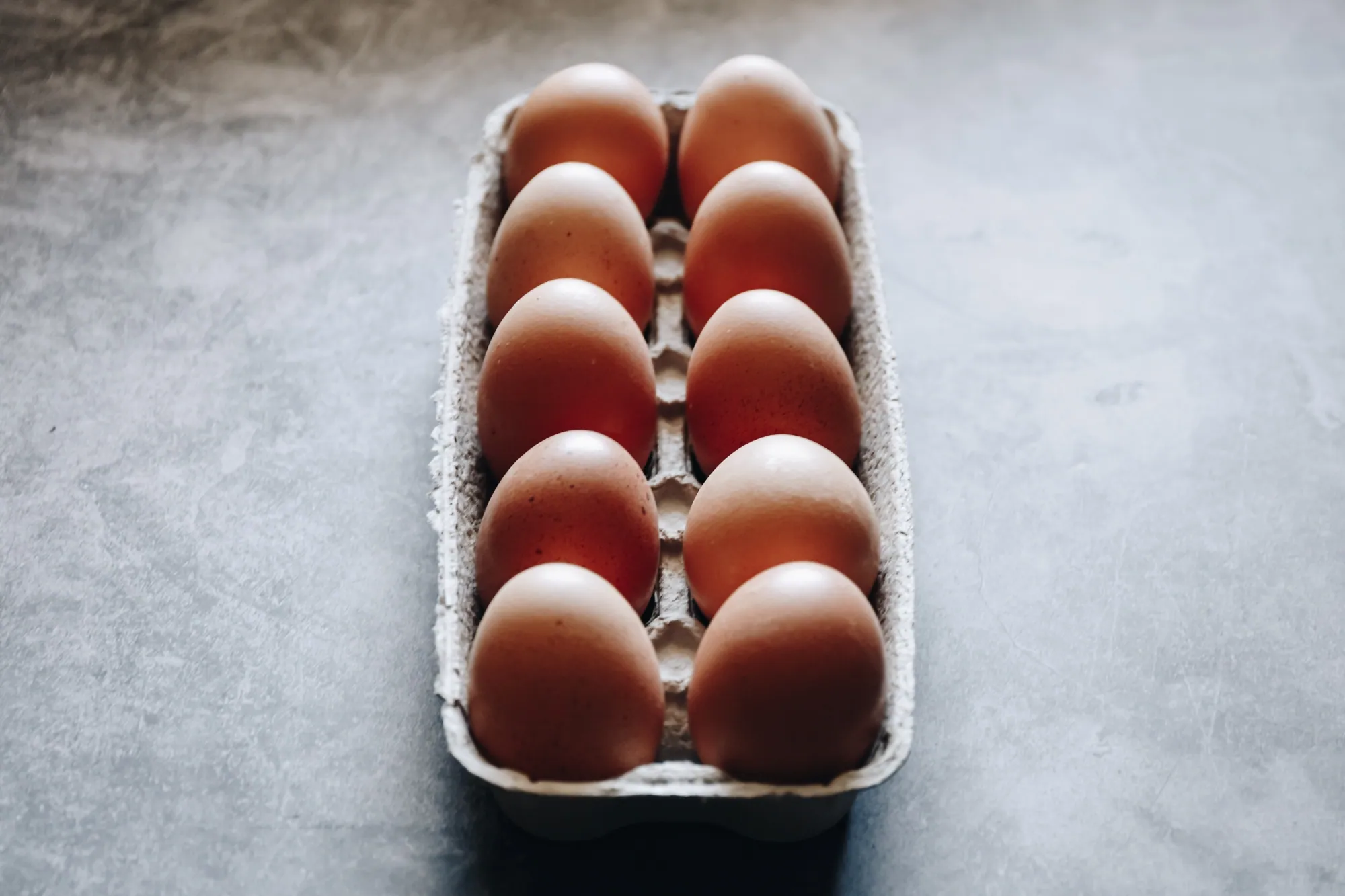 carton-of-brown-shelled-eggs-on-gray-surface-2026-03-17-00-42-36-utc